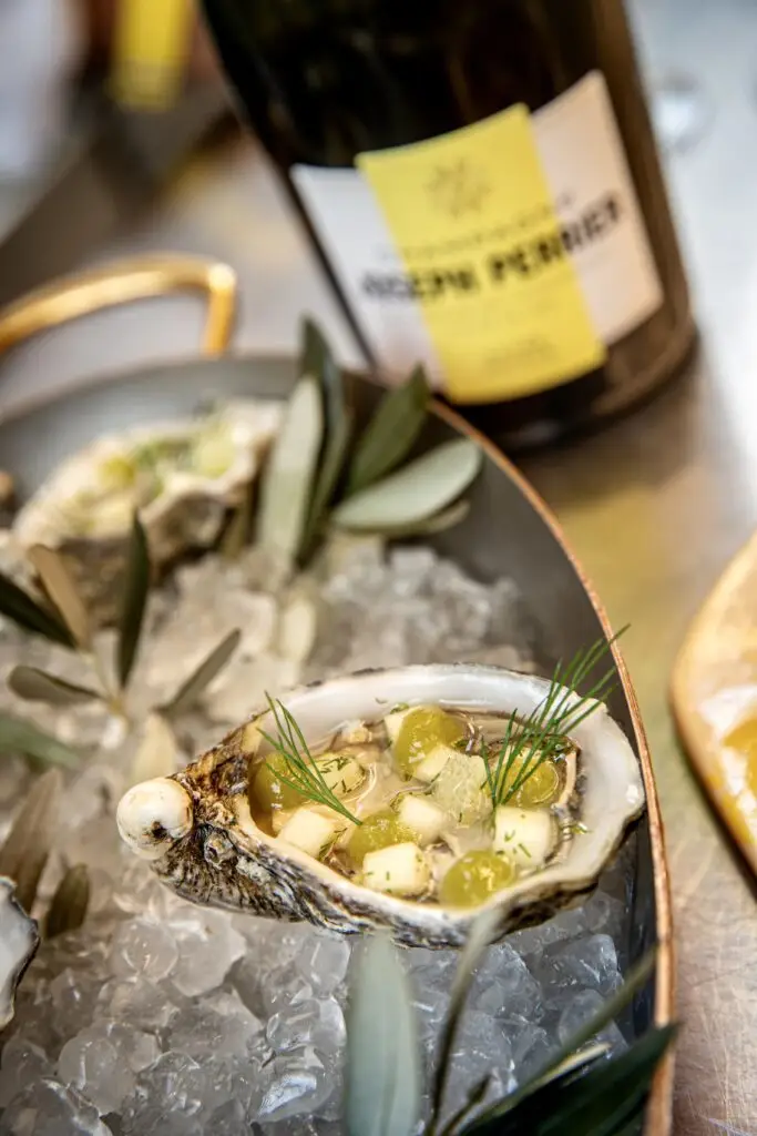 Oesters met groene appel, citroen en dille, geserveerd op een bedje van gemalen ijs.